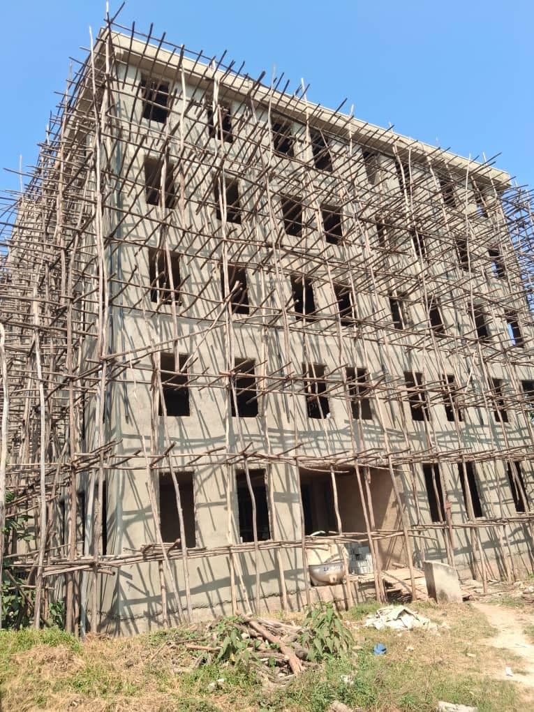 The four-story hospital building under construction, wrapped in scaffolding